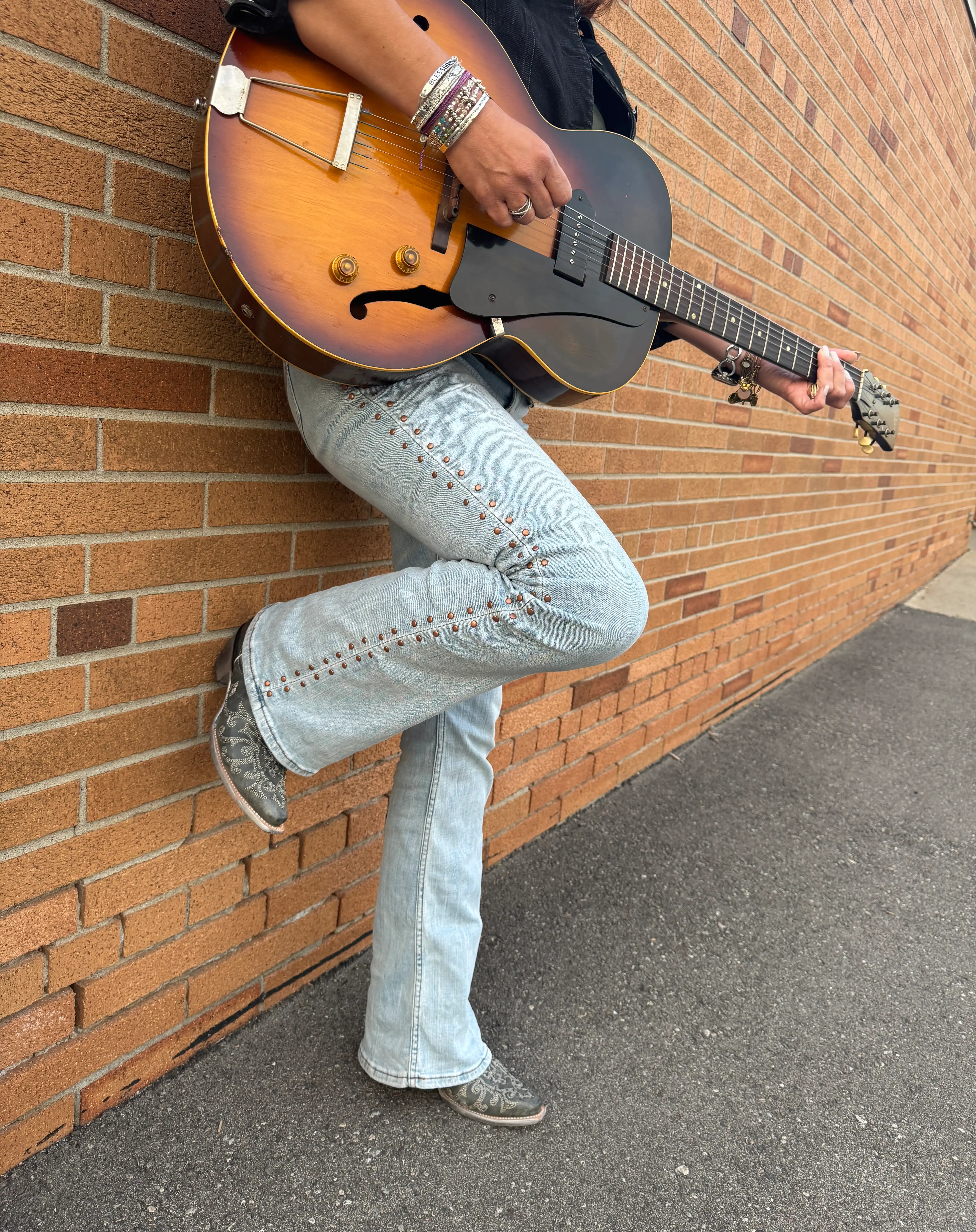 Country musician with guitar beside a brick wall decor piece